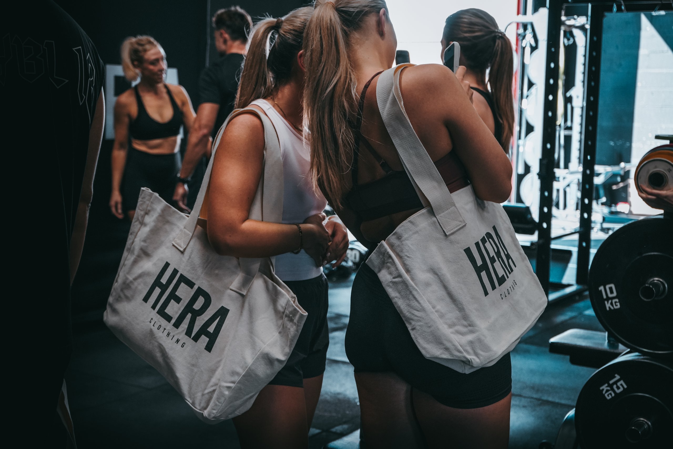 Two ladies holding HERA tote bags